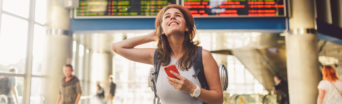 young woman smiling at looking at flight in airport