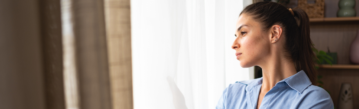 woman looking out of window opening curtain